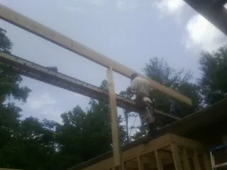 Carpenter setting a ridge beam over a new addition frame — Ice Dam Removal by Roofing Brothers in Clay Center