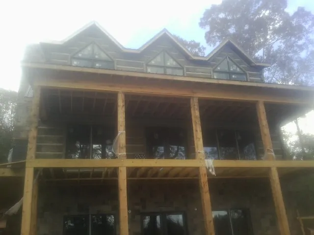 Dormers and porch framing on a large log home under construction — Roof Coating work by our crew in Clay Center