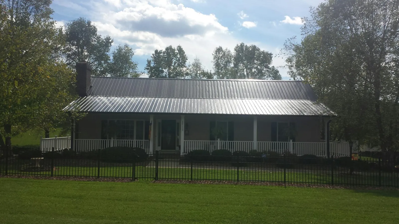 Gray metal roof on a brick ranch with a full width front porch — Gutter Guard Installation work by our crew in Clay Center